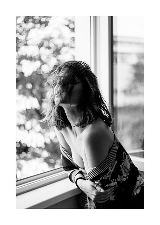 Zwart-wit foto van vrouw leunend op vensterbank in een off-shoulder top