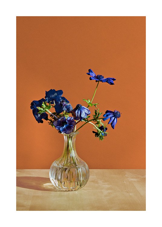  – Foto van een vaas met blauwe bloemen voor een oranje muur