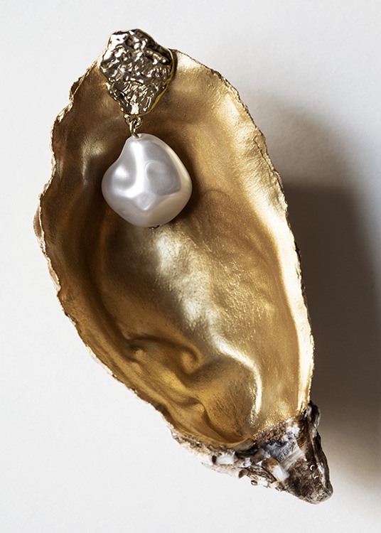  – Foto van een gouden schelp met een beschilderde binnenkant en een witte oorbel er bovenop