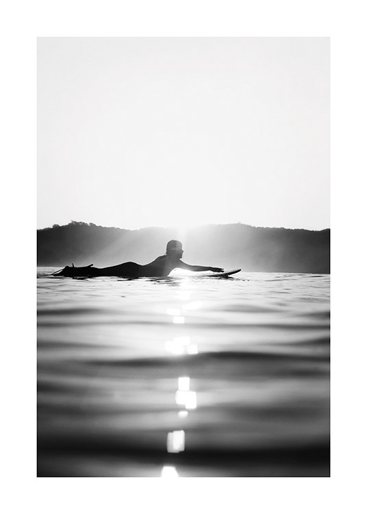 – Zwart-wit foto van een surfer die op een surfplank ligt in het water