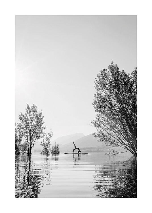  – Zwart wit foto van een vrouw in een yoga-positie op een surfplank in het midden van een meer