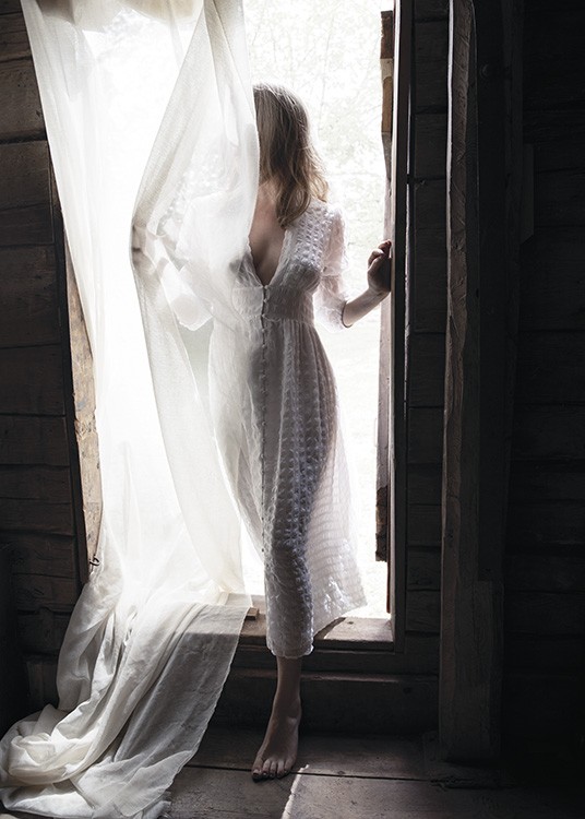 – Foto van een vrouw die in een deuropening staat in een witte jurk bedekt door een gordijn