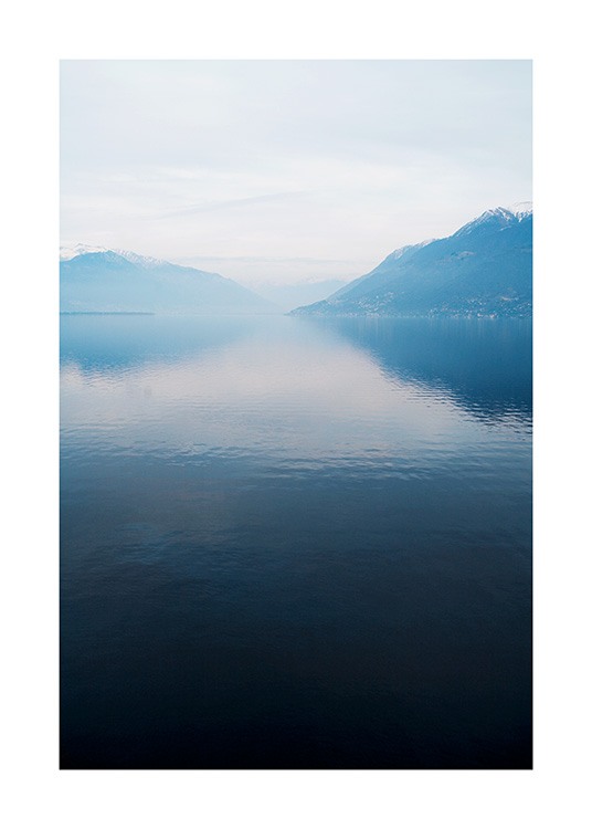  – Foto van een meer met een glad oppervlak, met bergen en mist op de achtergrond