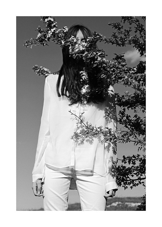  – Zwart-wit foto van een vrouw in witte kleren, met een tak voor haar