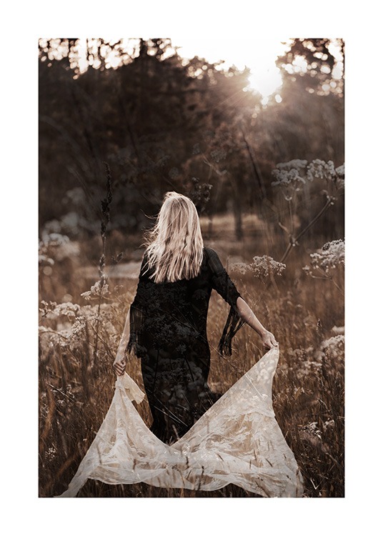  – Foto van een vrouw die in een veld loopt in een zwarte jurk en wit kant achter zich aan trekt