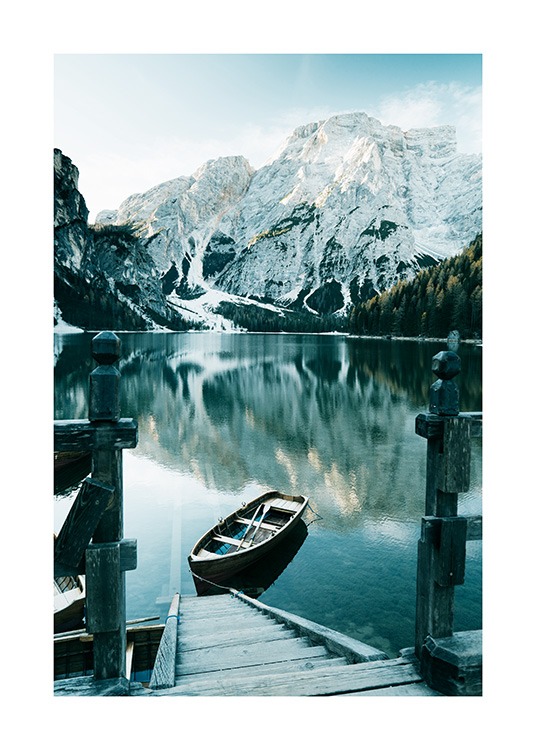  – Foto van besneeuwde bergen achter een meer met een boot en een houten trap ervoor