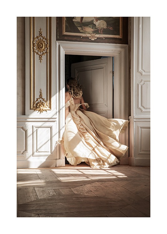  – Foto van een vrouw in een beige jurk die door een deur met barokke details loopt