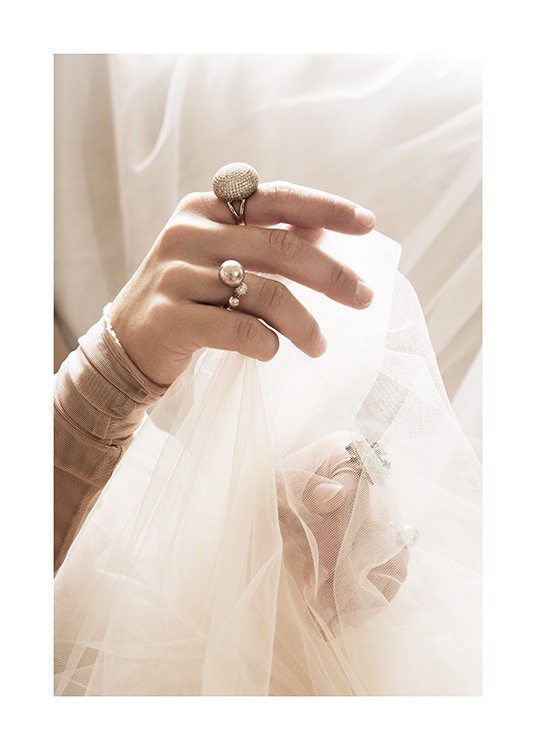  – Foto van een vrouw met ringen aan haar vingers, die witte tule stof in haar handen houdt