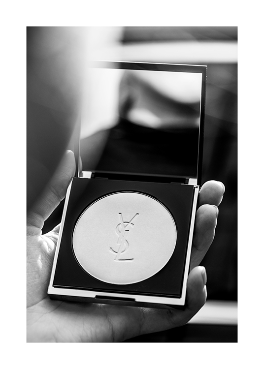  – Zwart-wit foto van iemand die een YSL poederdoos met een spiegel vasthoudt