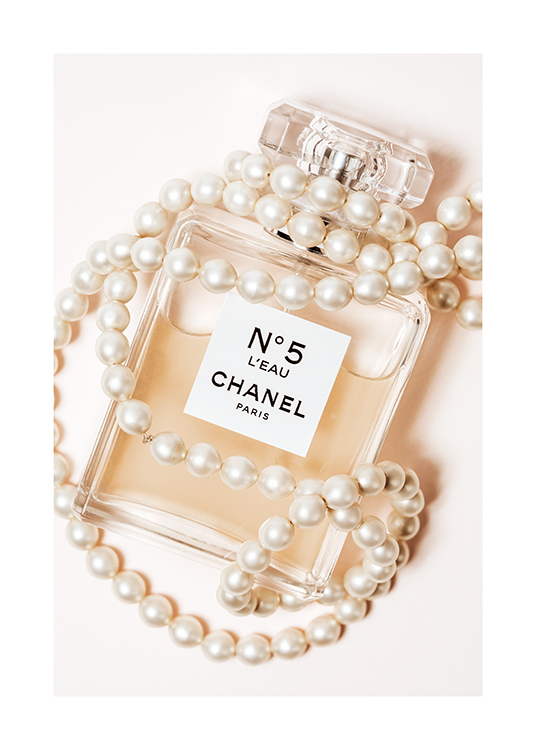  – Foto van een parfumfles waar Chanel No5 op geschreven staat, gewikkeld in een witte parelketting