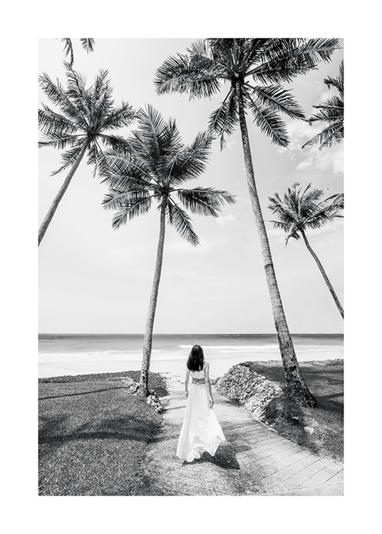  – Zwart-wit foto van een vrouw in een lange jurk die tussen palmbomen staat