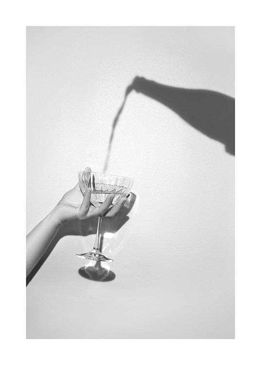  – Grijze foto van een schaduw van een champagnefles en een hand die een champagneglas vasthoudt