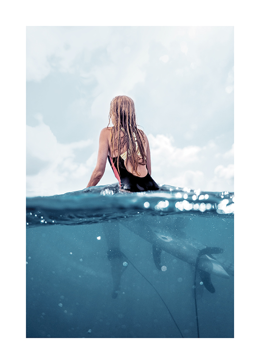  – Foto van een vrouw die op een surfplank in de oceaan dobbert, van achteren gezien