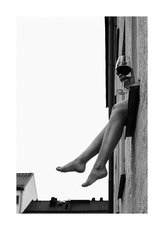  – Zwart-wit foto van een paar benen en hand met een glas wijn die uit een raam steken