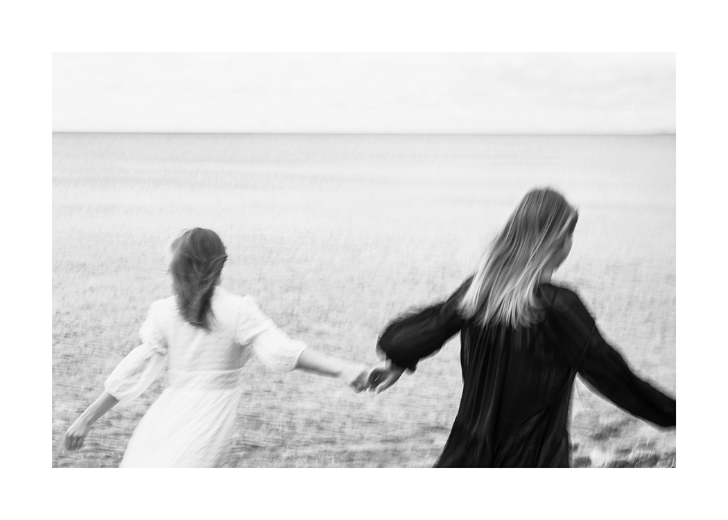 – Zwart-wit foto van een paar vrouwen die over een veld rennen terwijl ze elkaars handen vasthouden
